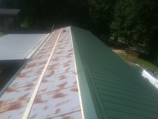 Old rusted panels beside newly installed green metal roofing — Wind Damage Roof Repair by Roofing Brothers in Amawalk