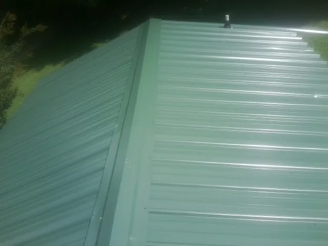 New green metal panels meeting at the ridge of a roof — Flat Roof Repair work by our crew in Amawalk