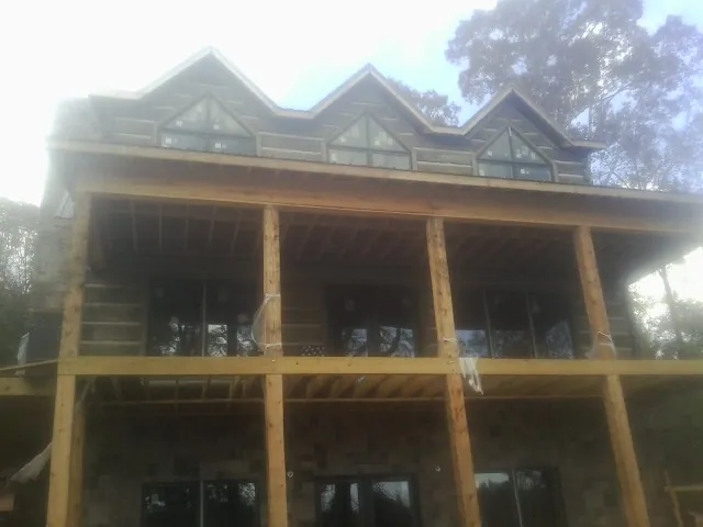 Dormers and porch framing on a large log home under construction — Roof Coating work by our crew in Amawalk