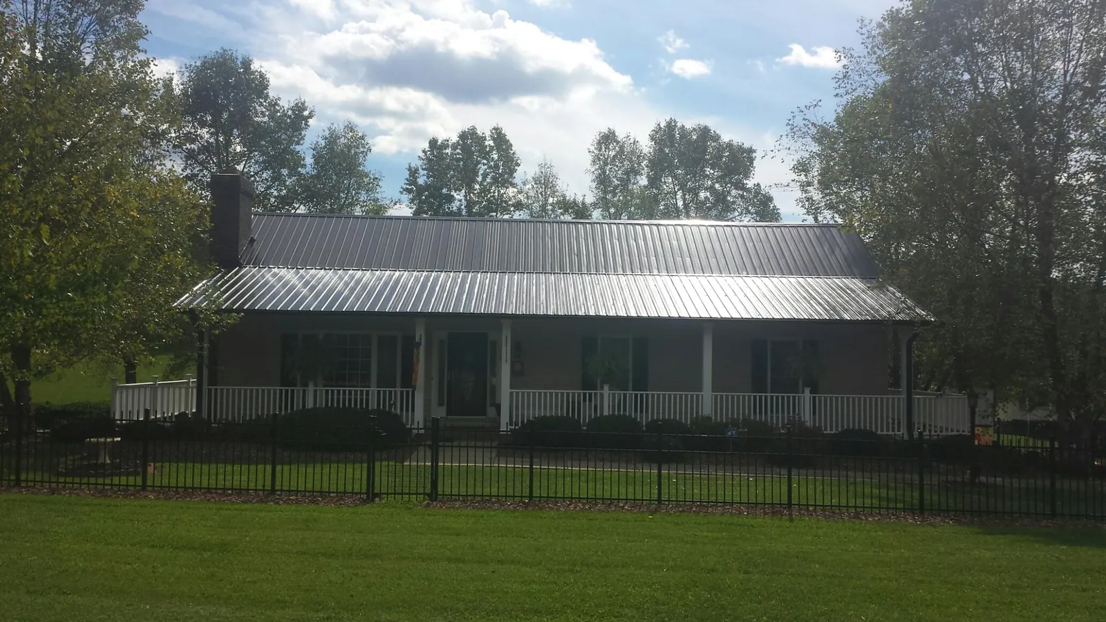 Gray metal roof on a brick ranch with a full width front porch — Gutter Guard Installation work by our crew in Amawalk