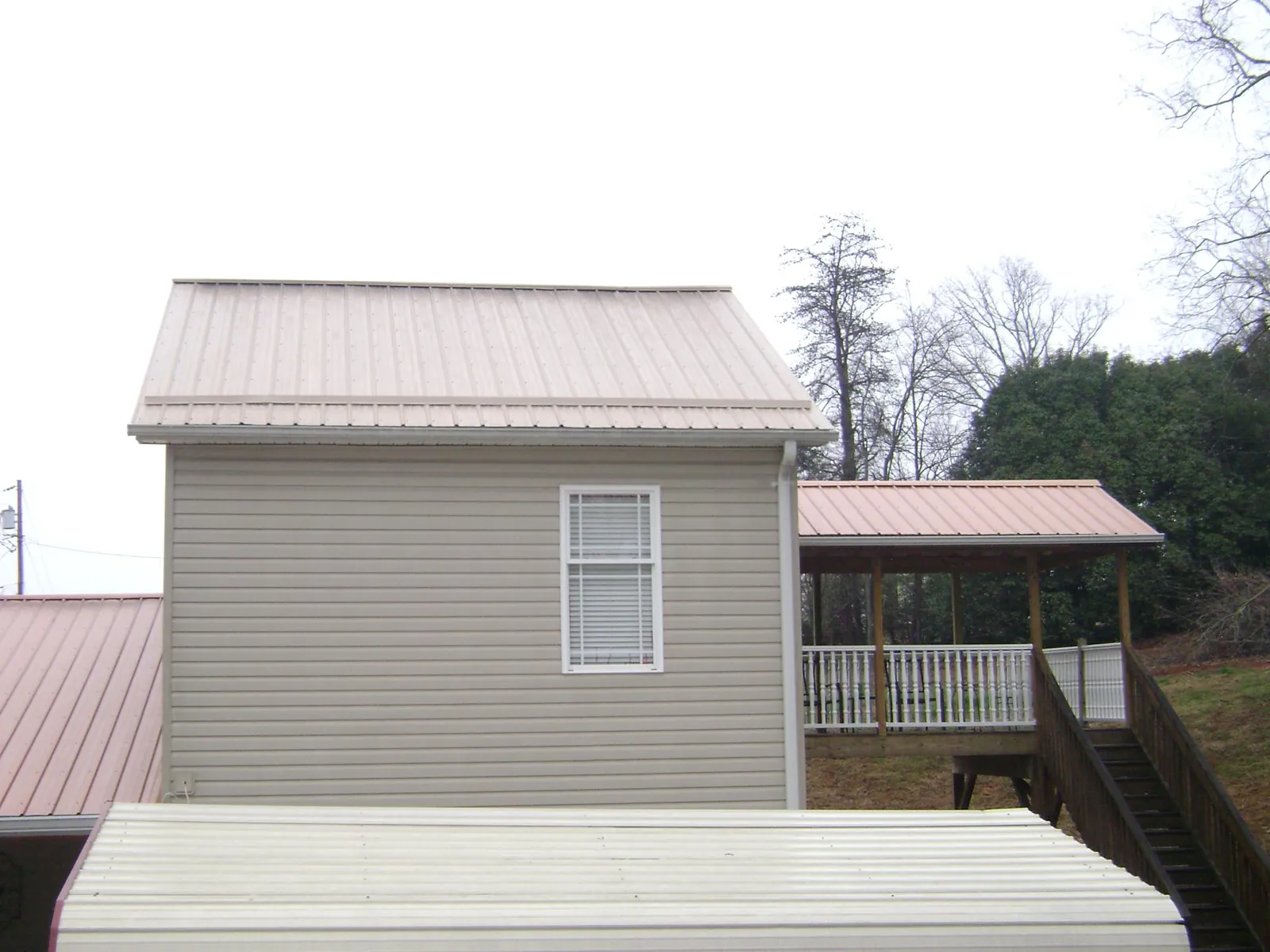 Tan metal roofs on a two story addition and attached porch, from a Roof Replacement job in Amawalk