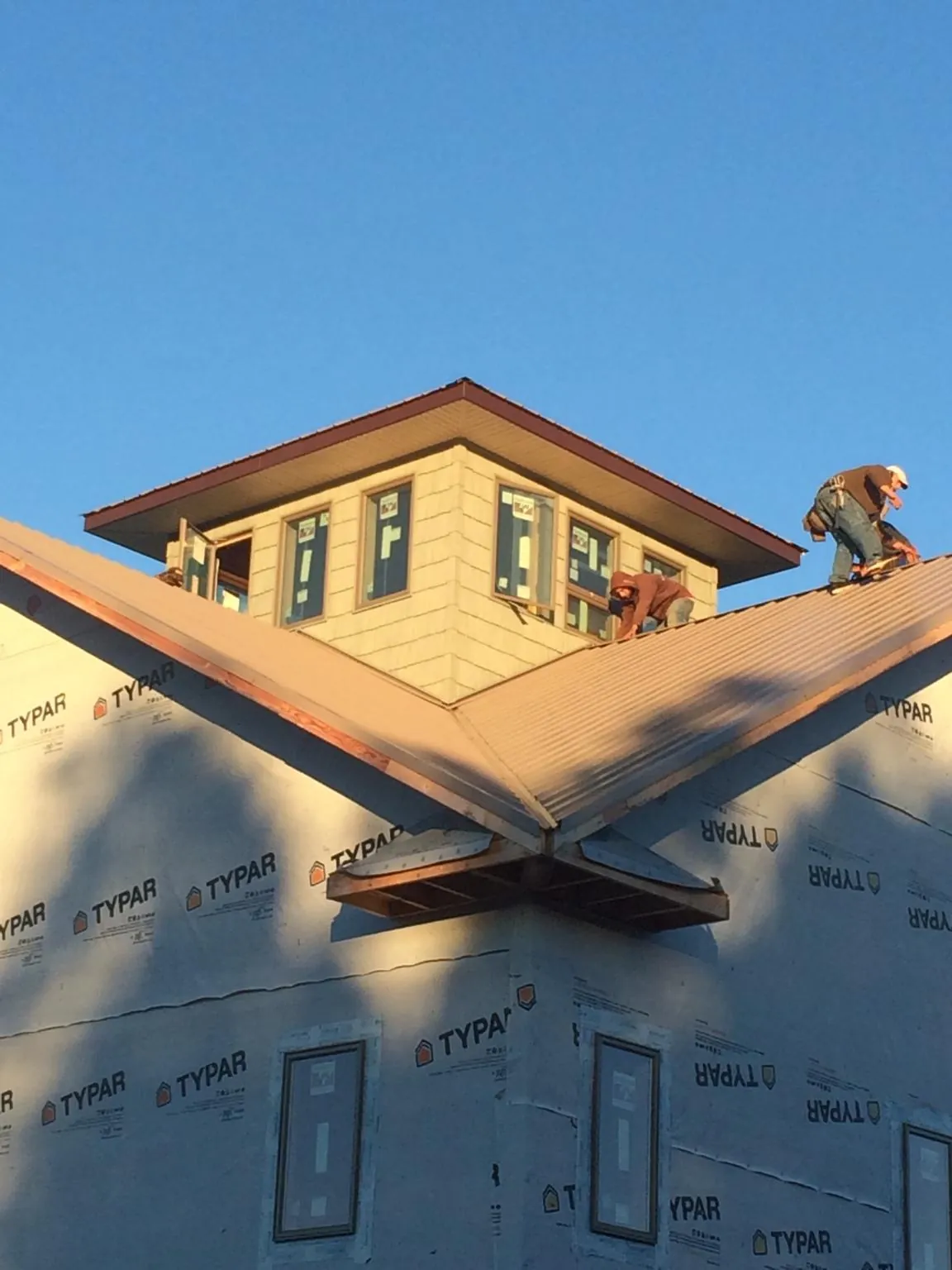 Roofers working around a rooftop cupola on a new metal roof at sunset — Roof Waterproofing in Amawalk by Roofing Brothers